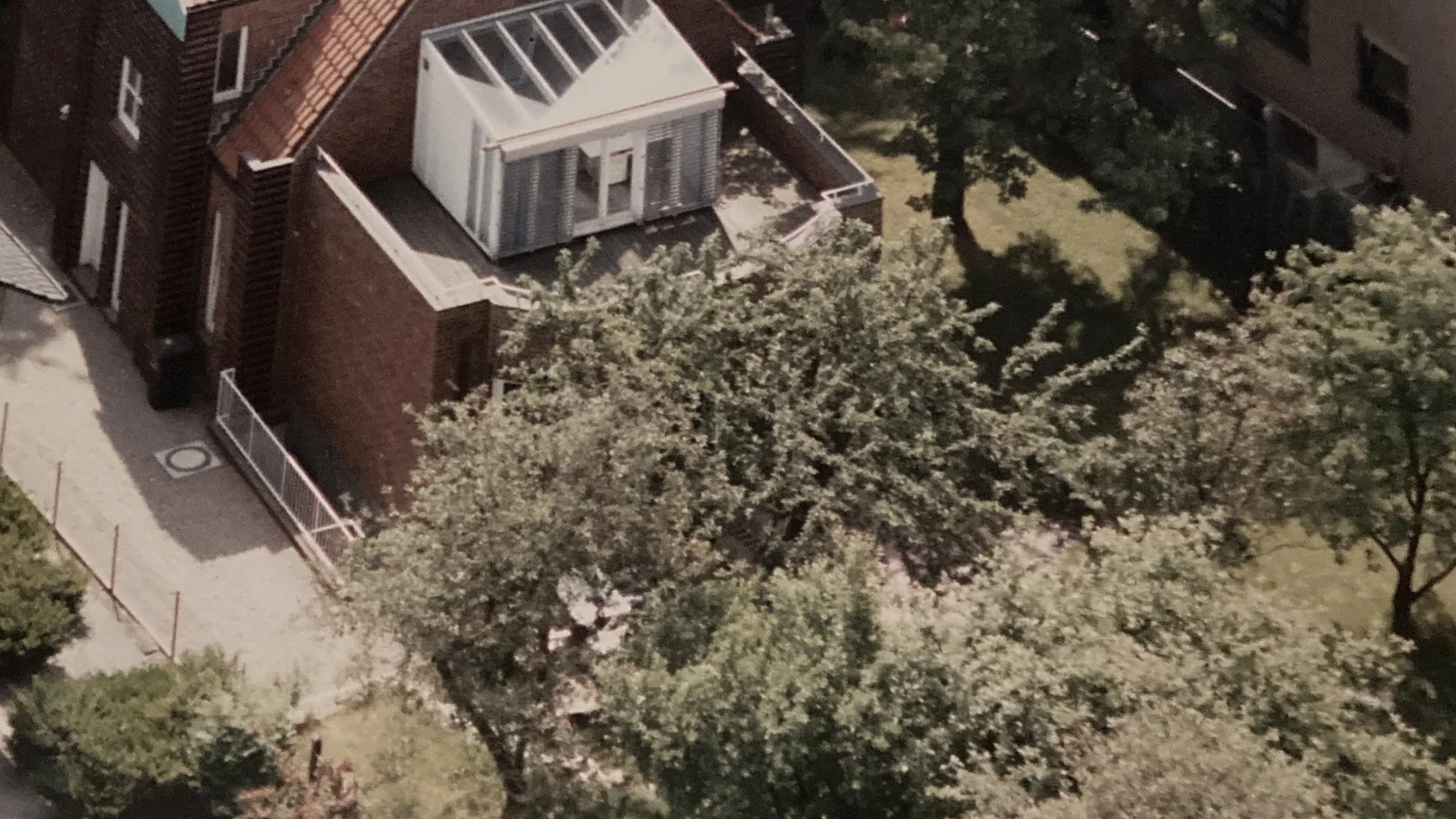 Drohnen-Luftaufnahme eines Wohnhauses mit Dachaufbau als Motiv für Drohnenvermessung und PV-Planung.
